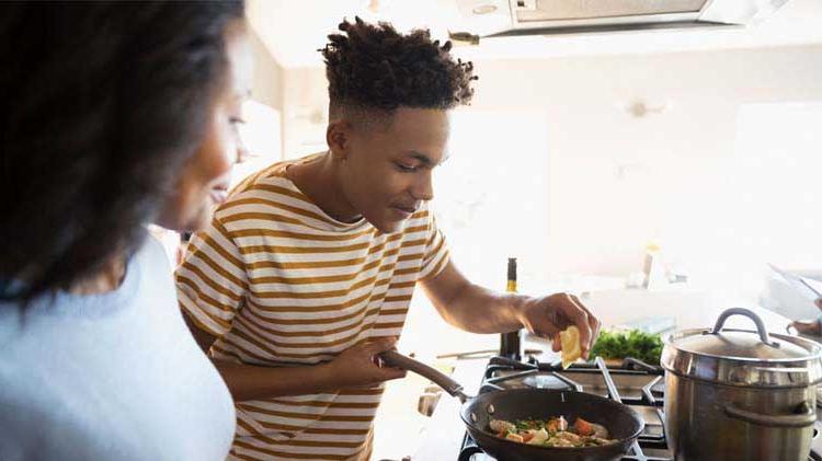 Adult child helping mom cook a meal.